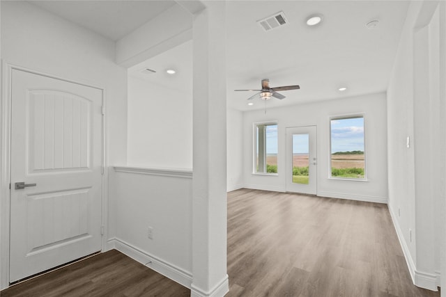 empty room with wood finished floors, visible vents, ceiling fan, and baseboards