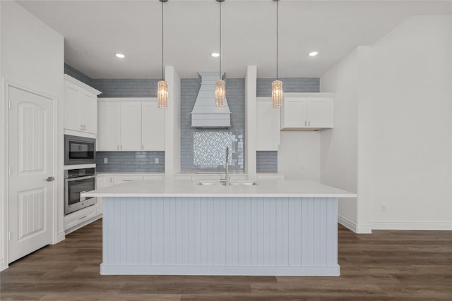 kitchen with a center island with sink, a sink, white cabinets, and oven