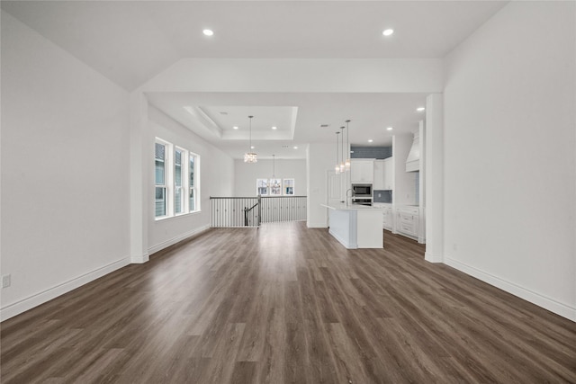 unfurnished living room featuring recessed lighting, a notable chandelier, baseboards, and dark wood finished floors