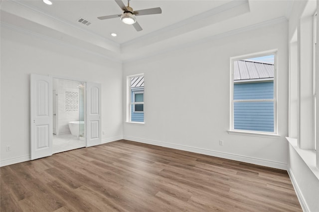 unfurnished bedroom featuring wood finished floors, crown molding, and a tray ceiling