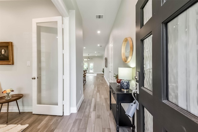 hall featuring visible vents, wood finished floors, and baseboards