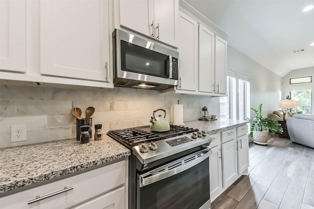 kitchen with open floor plan, white cabinetry, stainless steel appliances, and tasteful backsplash