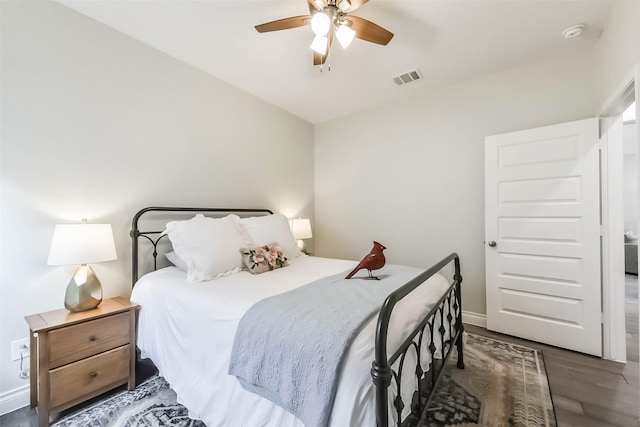 bedroom featuring ceiling fan, visible vents, vaulted ceiling, baseboards, and wood finished floors