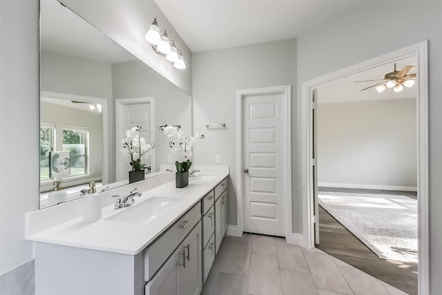 bathroom with baseboards, a ceiling fan, double vanity, and a sink