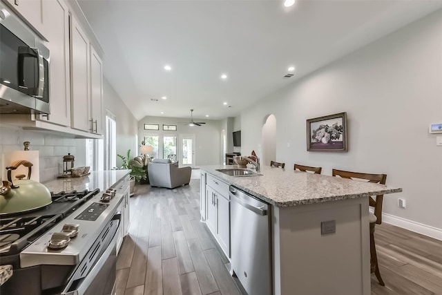 kitchen featuring a sink, appliances with stainless steel finishes, arched walkways, recessed lighting, and wood finished floors