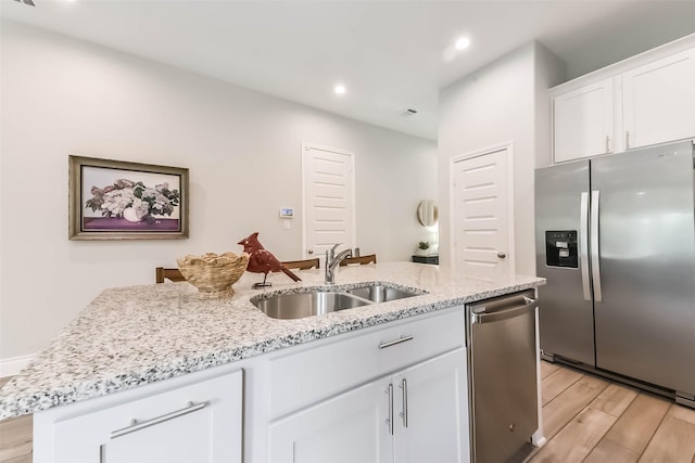 kitchen featuring light wood finished floors, recessed lighting, a sink, white cabinetry, and appliances with stainless steel finishes