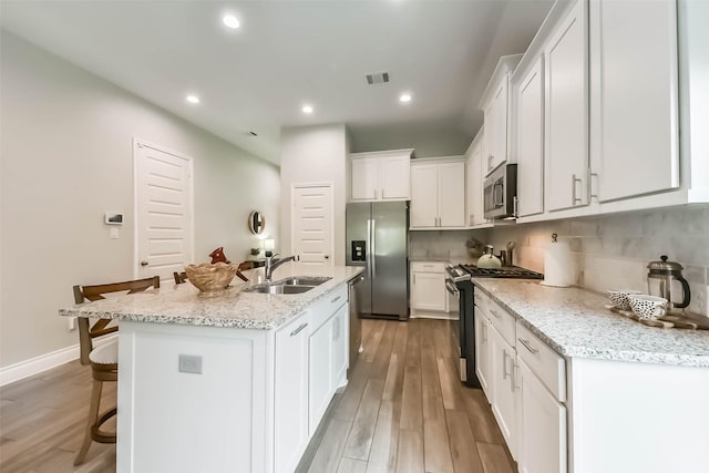 kitchen featuring visible vents, light wood-style floors, appliances with stainless steel finishes, and a sink