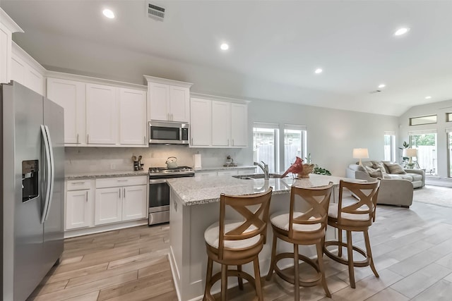 kitchen with light wood-style floors, appliances with stainless steel finishes, white cabinets, a sink, and visible vents