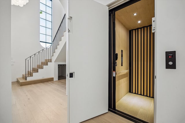 hallway featuring elevator, stairway, light wood-style floors, and recessed lighting