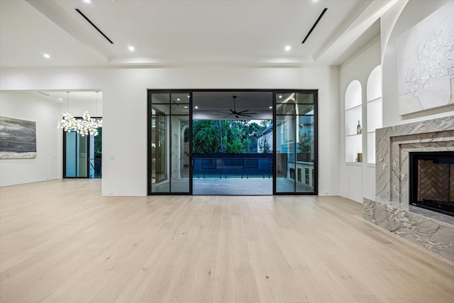 unfurnished living room with a notable chandelier, a premium fireplace, wood finished floors, and visible vents