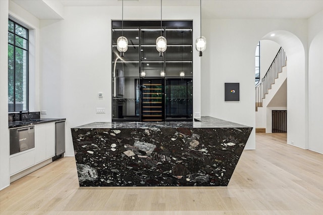 interior space with wood finished floors, stainless steel dishwasher, stairs, and arched walkways