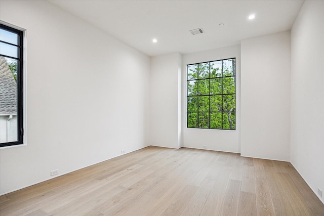 empty room with light wood finished floors, recessed lighting, and visible vents