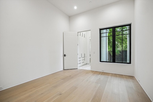 empty room with recessed lighting, a high ceiling, and light wood-type flooring