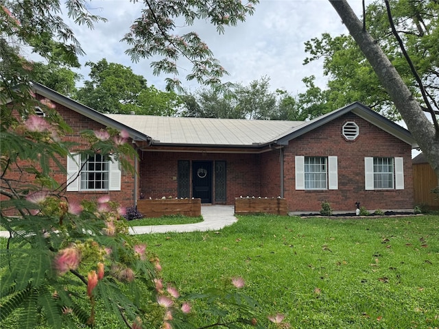 ranch-style house with metal roof, a porch, brick siding, and a front yard
