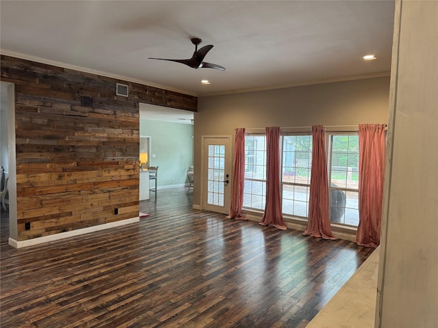 spare room featuring a ceiling fan, visible vents, baseboards, ornamental molding, and dark wood-type flooring