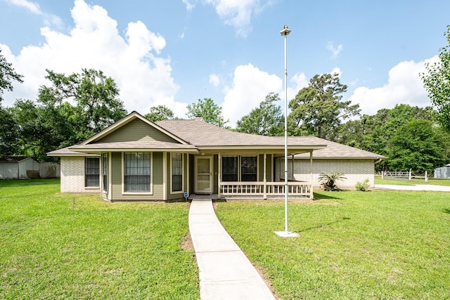 view of front facade featuring a front lawn, brick siding, covered porch, and roof with shingles