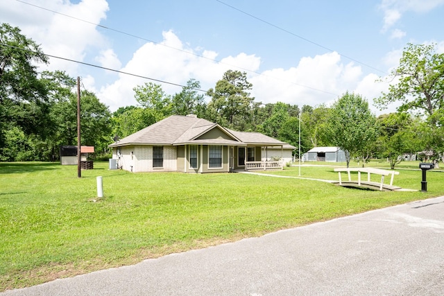 country-style home with covered porch, a shingled roof, and a front lawn
