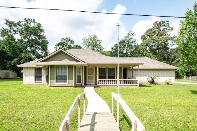view of front of home featuring covered porch, brick siding, fence, a shingled roof, and a front lawn