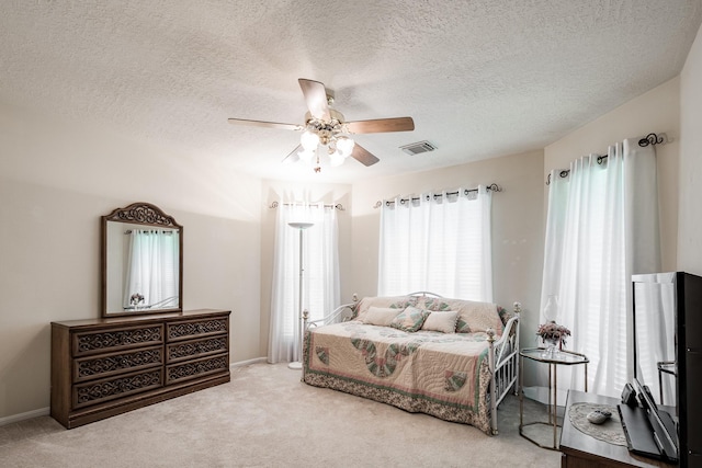 bedroom with a textured ceiling, ceiling fan, visible vents, baseboards, and carpet floors