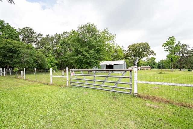 view of gate featuring fence, an outdoor structure, and a lawn
