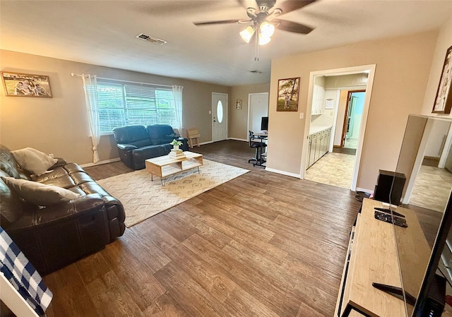 living area featuring visible vents, ceiling fan, wood finished floors, and baseboards