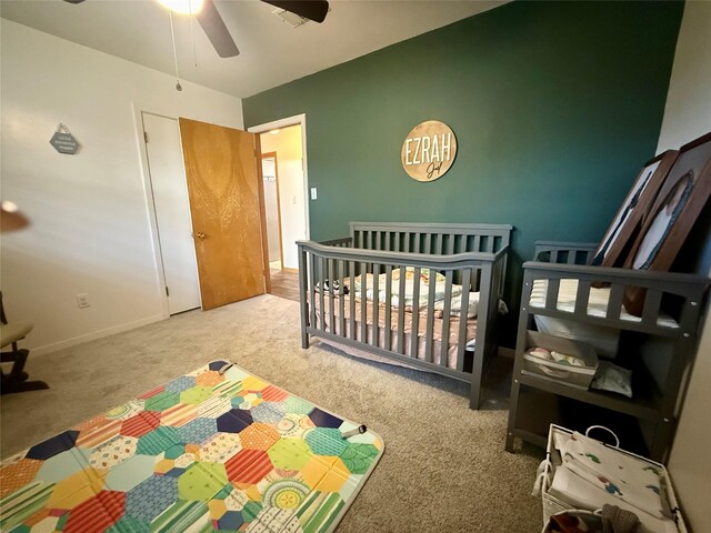bedroom with a crib, carpet flooring, ceiling fan, and baseboards