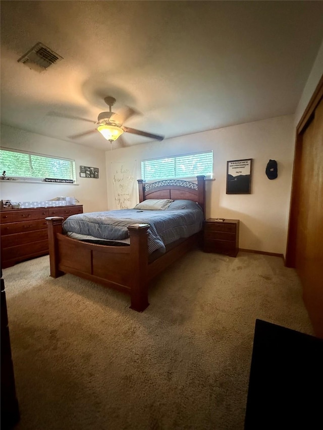 bedroom with visible vents, a closet, a ceiling fan, and light carpet