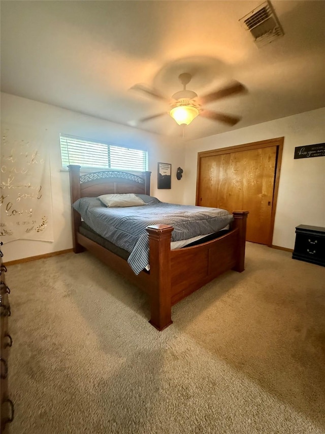 bedroom featuring a closet, a ceiling fan, visible vents, light carpet, and baseboards