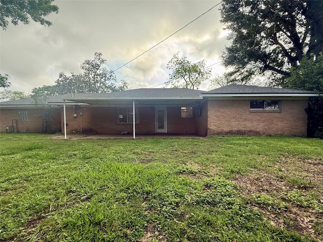 rear view of house with a patio, a yard, and brick siding
