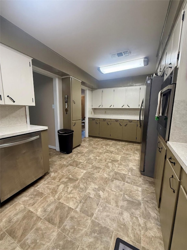 kitchen featuring stone finish floor, appliances with stainless steel finishes, light countertops, white cabinets, and visible vents