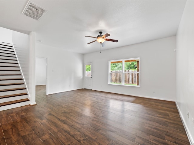 unfurnished living room featuring dark wood-type flooring, a ceiling fan, visible vents, stairs, and baseboards