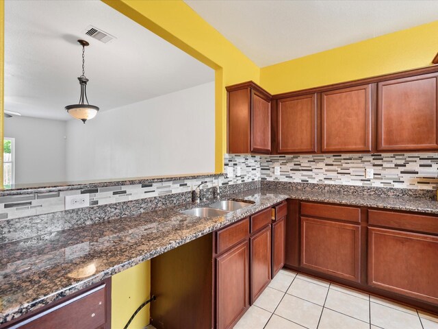 kitchen with dark stone counters, decorative backsplash, a sink, visible vents, and pendant lighting