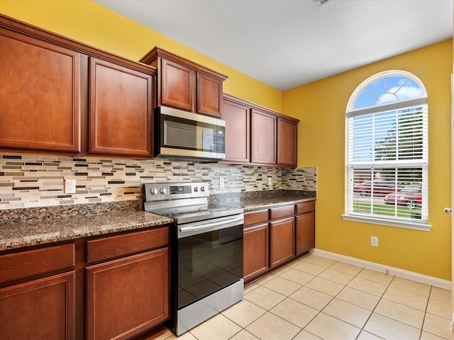 kitchen featuring baseboards, light tile patterned floors, backsplash, and appliances with stainless steel finishes