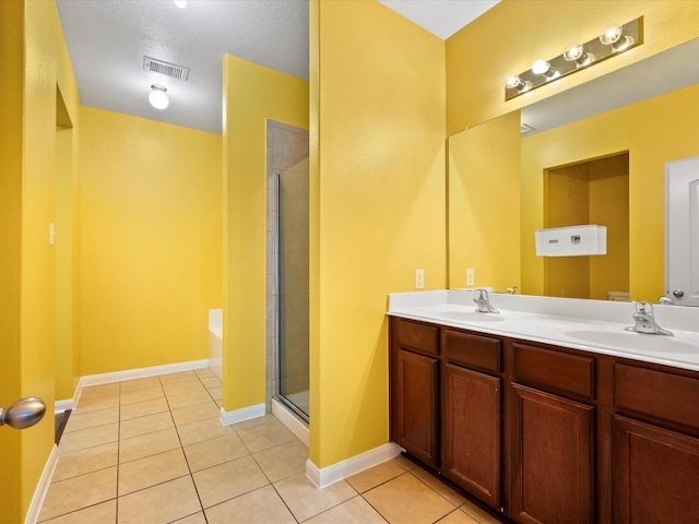 bathroom with tile patterned floors, a shower with shower door, double vanity, and a sink