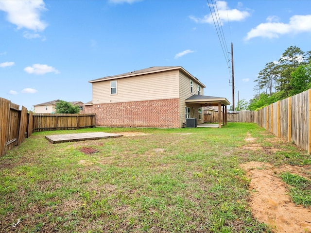 back of property featuring a lawn, a fenced backyard, and brick siding