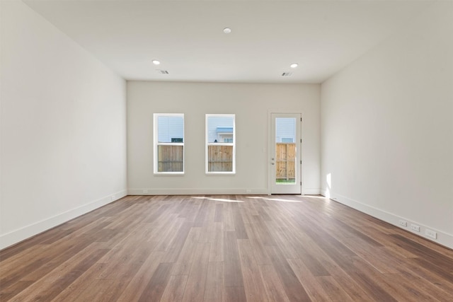 empty room with recessed lighting, visible vents, wood finished floors, and baseboards