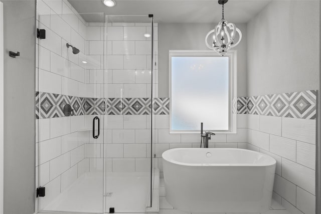 full bathroom with tile walls, a freestanding tub, a chandelier, and a shower stall