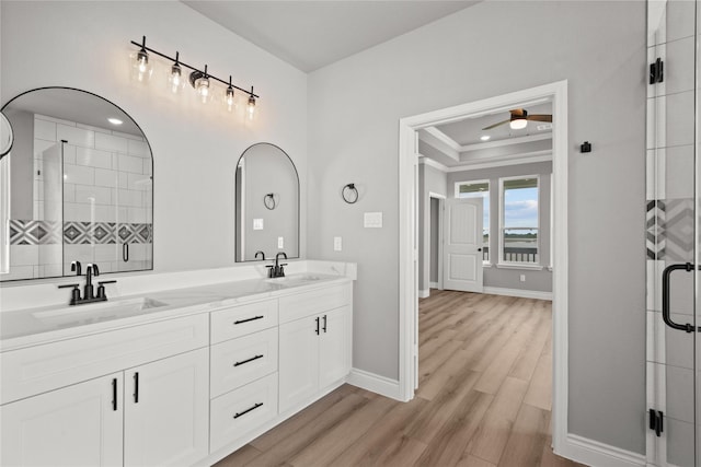 full bathroom featuring a sink, a stall shower, a ceiling fan, baseboards, and wood finished floors