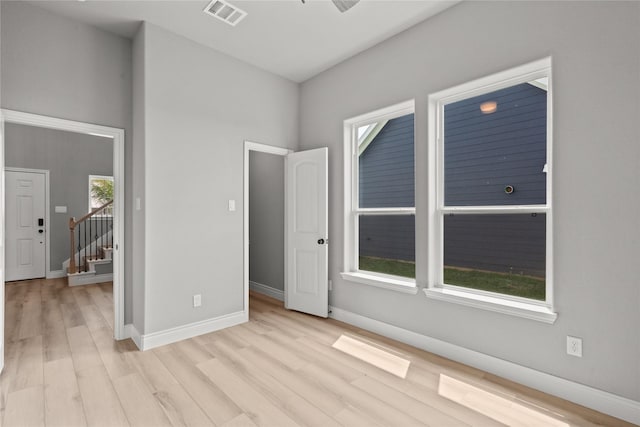 empty room with stairs, visible vents, wood finished floors, and baseboards