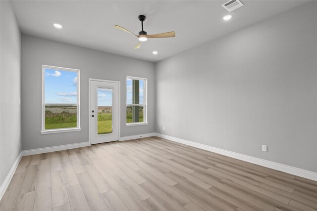 empty room featuring visible vents, light wood-type flooring, a ceiling fan, and baseboards