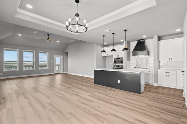 kitchen with premium range hood, recessed lighting, backsplash, and a tray ceiling