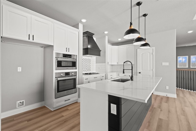kitchen featuring light wood finished floors, a sink, white cabinets, and baseboards