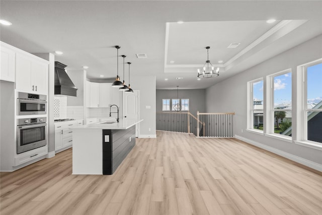 kitchen featuring recessed lighting, a raised ceiling, an inviting chandelier, and stainless steel double oven