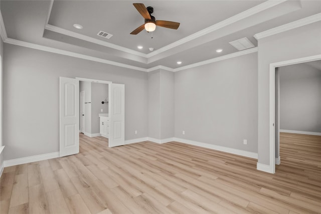 unfurnished bedroom featuring ornamental molding, visible vents, light wood-type flooring, and a tray ceiling