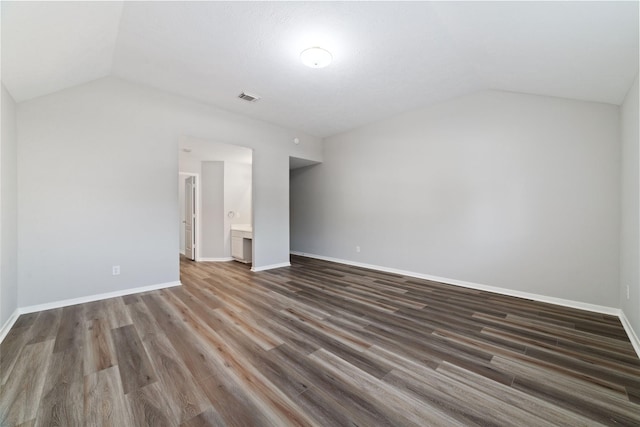interior space featuring dark wood-style floors, visible vents, lofted ceiling, and baseboards