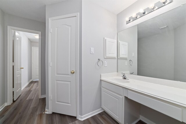 bathroom featuring baseboards, wood finished floors, and vanity