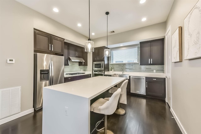 1812 Bingham St, Houston, TX 77007 - kitchen with under cabinet range hood, dark brown cabinetry, visible vents, light countertops, and appliances with stainless steel finishes