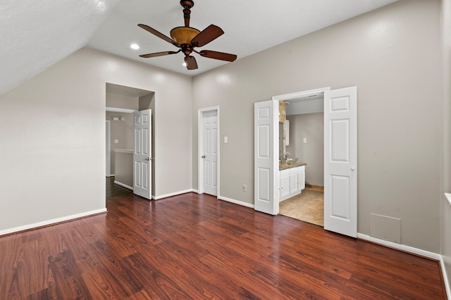 unfurnished bedroom with dark wood-type flooring, ensuite bathroom, baseboards, a ceiling fan, and lofted ceiling
