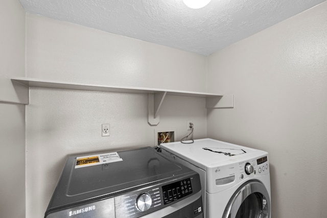 washroom featuring a textured ceiling, laundry area, and washing machine and dryer