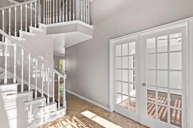 entrance foyer with a towering ceiling, stairs, french doors, and baseboards